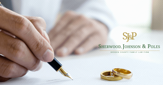 hand with pen signing paper and wedding rings